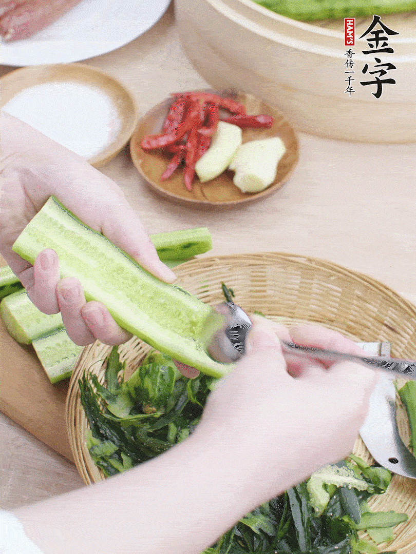 黃瓜削皮，對半切開，勺子挖去內(nèi)瓤，斜刀切片。青蒜斜刀切段。